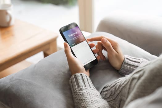 CHIANG MAI, THAILAND - APR 24, 2023: A woman holds Apple iPhone with Instagram application on the screen at home. Instagram is a photo-sharing app for smartphones.