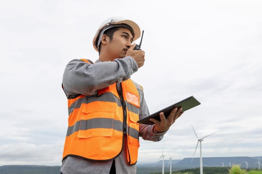 Engineer working on a wind farm atop a hill or mountain in the rural. Progressive ideal for the future production of renewable, sustainable energy. Energy generation from wind turbine.