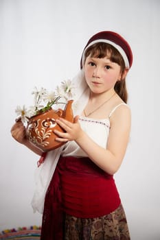 Portrait of Little girl in a stylized Tatar national costume with flowers on a white background in the studio. Photo shoot of funny young teenager who is not a professional model