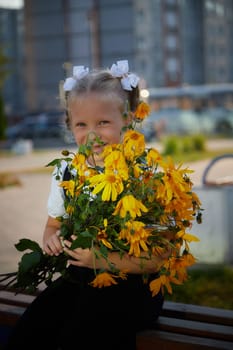 Little girl of elementary school student in modern school uniform outdoors with bouquet of flowers. Female child schoolgirl going to school. Back to school in september 1 in Russia