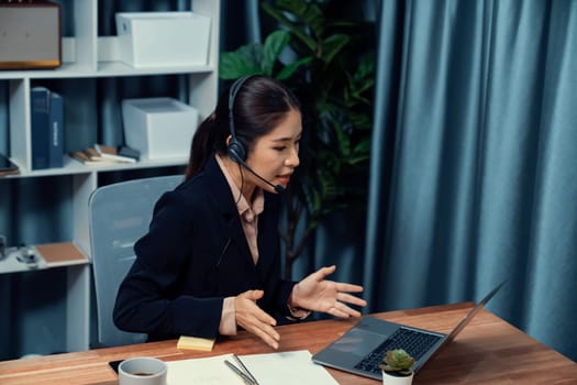 Asian call center with headset and microphone working on her laptop. Female operator provide exceptional customer service. Supportive call center agent helping customer on inquiry. Enthusiastic