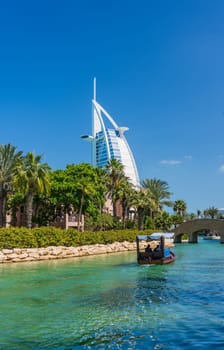 Boat tour along waterway around Souk Madinat Jumeirah in Dubai with iconic Arab hotel in background