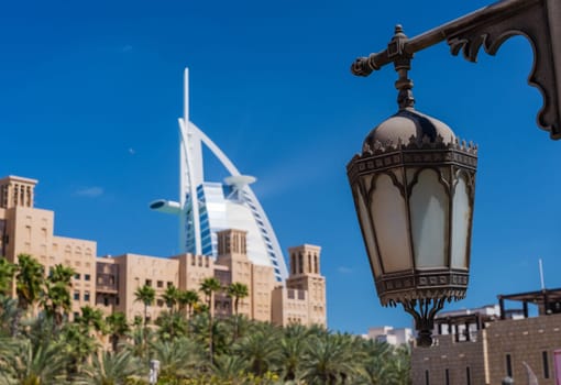 Iconic Burj Arab hotel in background behind arabic buildings in Souk Madinat Jumeirah