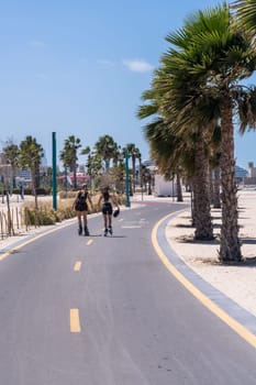 Two women roller blading along cycle track at Jumeirah Wild public beach in Dubai UAE