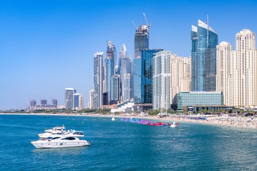 Tourists on JBR beach in Jumeirah area of Dubai with panorama of hotels and apartments behind