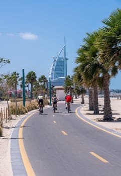 Three cyclists ride along cycle track at Jumeirah Wild public beach in Dubai UAE