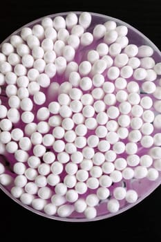 Can with cotton buds on a black wooden background