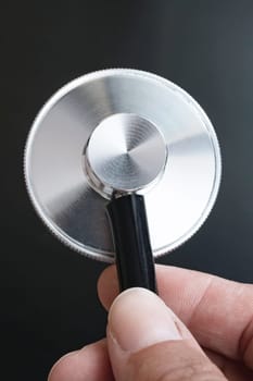 Medical stethoscope in hand on black background close up