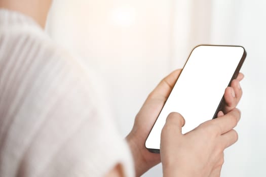 Asian woman's hand using a smartphone with blank white screen for the concept of business, communication and media technology.