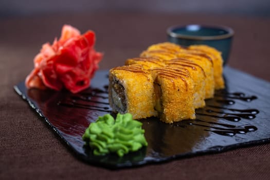 baked rolls with salmon and tender cheese with sauce on a black plate.