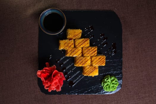 baked rolls with salmon and tender cheese with sauce on a black plate top view.