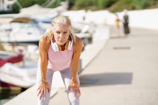 Mature sportswoman taking a break during exercise. Concept of healthy living in the elderly. Senior woman in fitness clothing. Older female doing sport to keep fit.