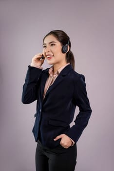 Attractive asian female call center operator with happy smile face advertises job opportunity on empty space, wearing a formal suit and headset on customizable isolated background. Enthusiastic