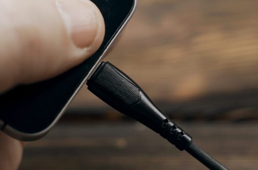 Close-up of connecting charging to the phone. Phone charging by wire.