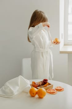 A girl in a white coat holds in her hands a strip of fruit marshmallow taken from a gift set.