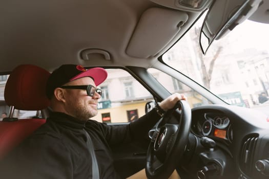 The man with glasses and cap driving car.