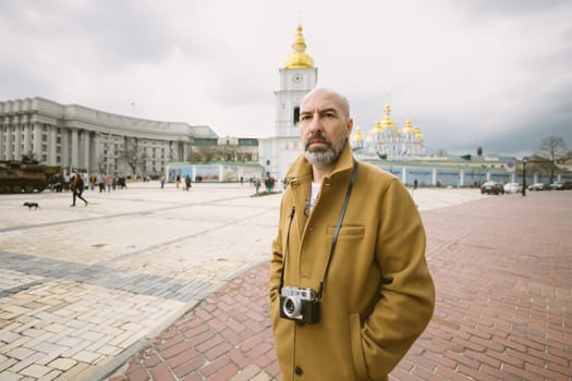 Handsome beard photographer makes pictures on film retro camera in the Kyiv city, Ukraine