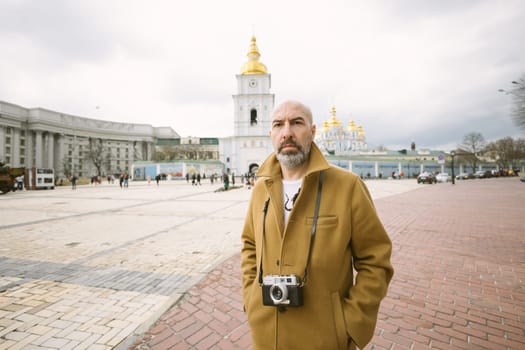Handsome beard photographer makes pictures on film retro camera in the Kyiv city, Ukraine