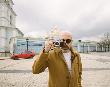 Handsome beard photographer makes pictures on film retro camera in the Kyiv city, Ukraine