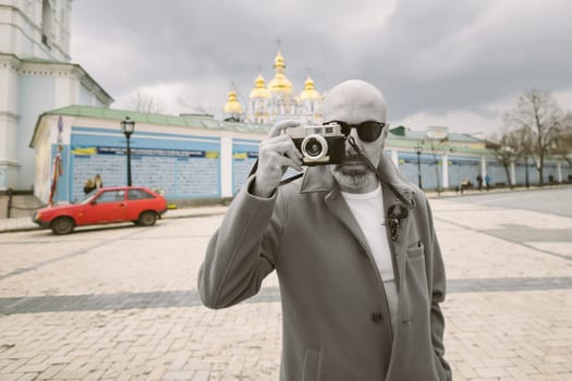 Handsome beard photographer makes pictures on film retro camera in the Kyiv city, Ukraine