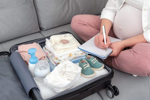 Pregnant woman writing packing list for maternity hospital at home