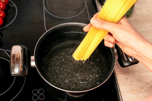 a female hostess in the kitchen cooks delicious spaghetti. Cooking Italian spaghetti in the kitchen. italian cooking concept