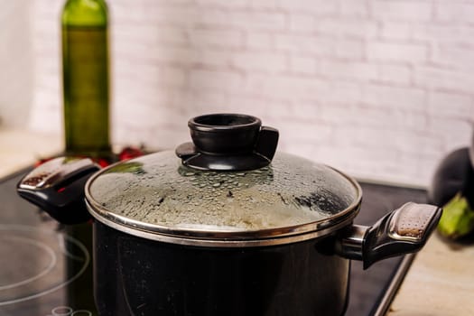 condensation drops on the transparent glass lid of the kitchen pot boiling on the stove. Close up. the misted lid of a pot of boiling water. Moist condensation from boiling water on the transparent glass lid of the kitchen pan while cooking