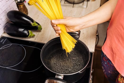 a female hostess in the kitchen cooks delicious spaghetti. Cooking Italian spaghetti in the kitchen. italian cooking concept