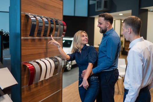 The seller helps a married couple choose the color of a new car