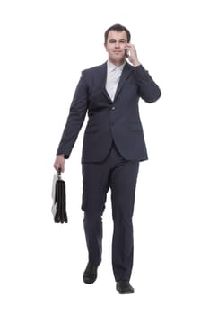 Front view of handsome young business man talking on a mobile phone and holding a suitcase on white background