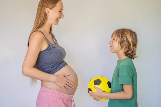 Amusing son. Pregnant beautiful woman amusing her little son while putting yellow ball under his green shirt.