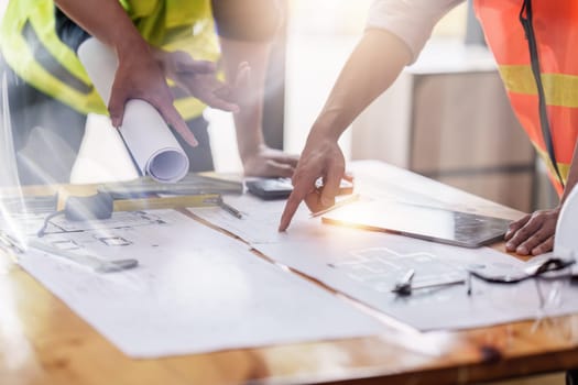 Architect and Engineer working with blueprints for architectural plan, engineer sketching a construction project, green energy concept.