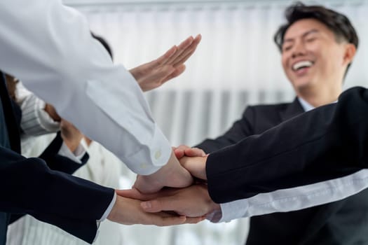 Bottom view partial hands wearing formal suit joining stack as symbol of team building, unity and harmony in office workplace. Successful business team of synergy holding hand together