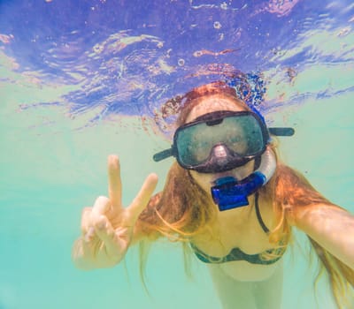 Pregnant woman underwater swimming in tropical sea. Healthy and active pregnancy. Young expecting mom on summer beach vacation before baby birth. Swim holiday and water fun. Travel during pregnancy. Underwater photography.