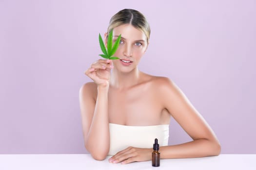 Alluring portrait of beautiful woman in pink isolated background holding green leaf with marijuan extracted bottle for skincare treatment product. Cannabis CBD oil for cosmetology and beauty concept.