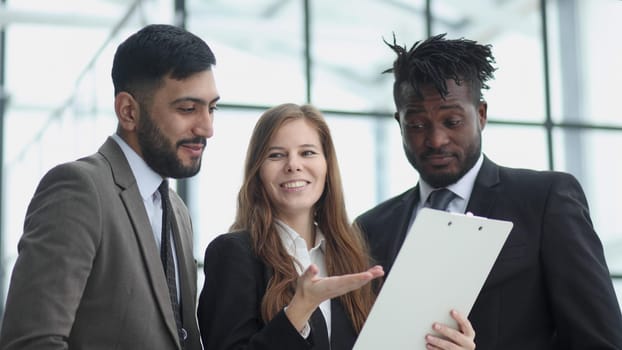Portrait of three people in business wear discussing document in office.