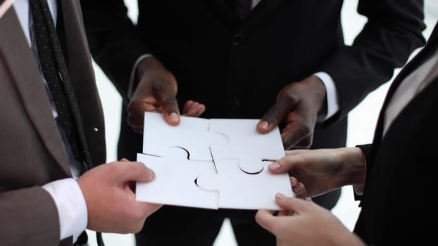 five hands of businessmen put together a puzzle.