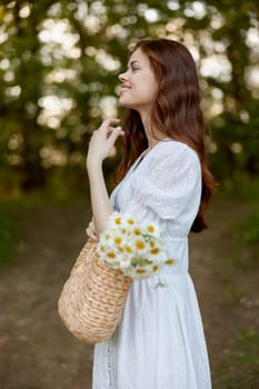 portrait of a beautiful red-haired woman with a wicker bag in her hands, smiling, enjoying a walk in the park. High quality photo