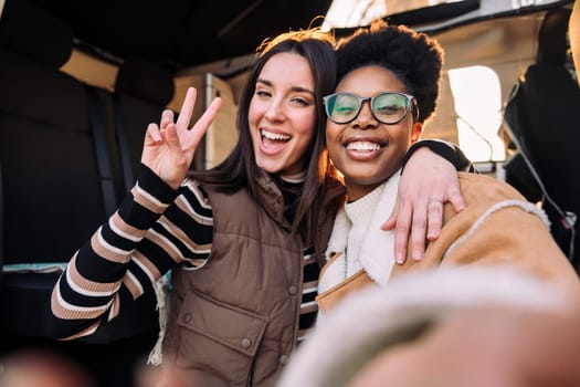 selfie photo of two happy women having fun in camper van during a road trip, concept of weekend getaway and female friendship