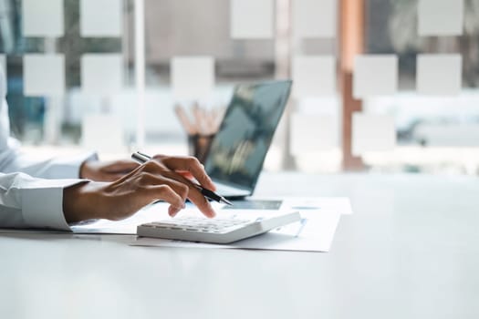 Business woman using calculator for do math finance on wooden desk in office and business working background, tax, accounting, statistics and analytic research concept.