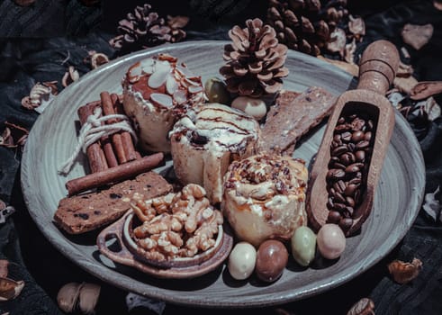 Bakery, Stick cookies, Walnuts, Roasted coffee beans, Colored eggs and Pine cones on Ceramic plate with dark background. Easter desserts, Selective focus.