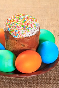 Easter cake and painted eggs on a plate with sackcloth on the background. Traditional orthodox christian easter food.
