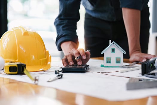 Architect working with blueprints for architectural plan, engineer sketching a construction project, green energy concept.