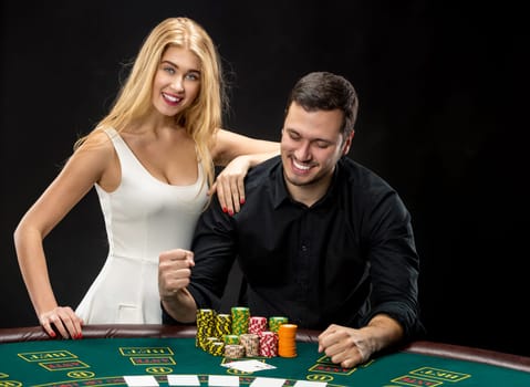 Young couple playing poker and have a good time in casino, woman embracing man.