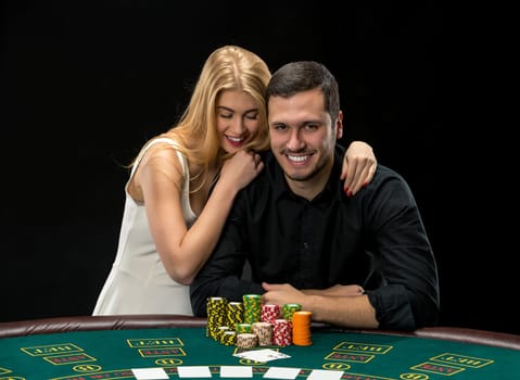 Young couple playing poker and have a good time in casino, woman embracing man.