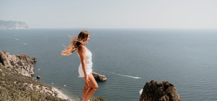 Woman travel sea. Young Happy woman in a long red dress posing on a beach near the sea on background of volcanic rocks, like in Iceland, sharing travel adventure journey