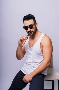 Close-up bearded caucasian man smoking cigar. Wearing white shirt. Studio portrait