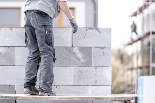 a mason builds the wall of a building from concrete bricks and blocks. High quality photo
