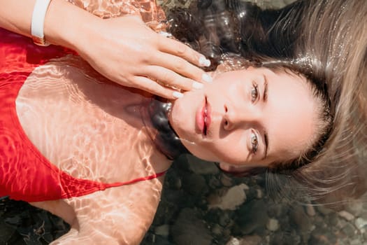 Side view a Young beautiful sensual woman in a mint long dress posing on a volcanic rock high above the sea during sunset. Girl on the nature on overcast sky background. Fashion photo