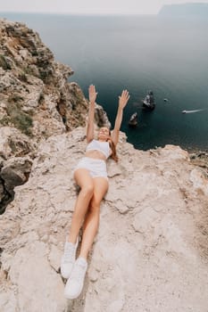 Woman travel sea. Happy tourist in hat enjoy taking picture outdoors for memories. Woman traveler posing on the beach at sea surrounded by volcanic mountains, sharing travel adventure journey